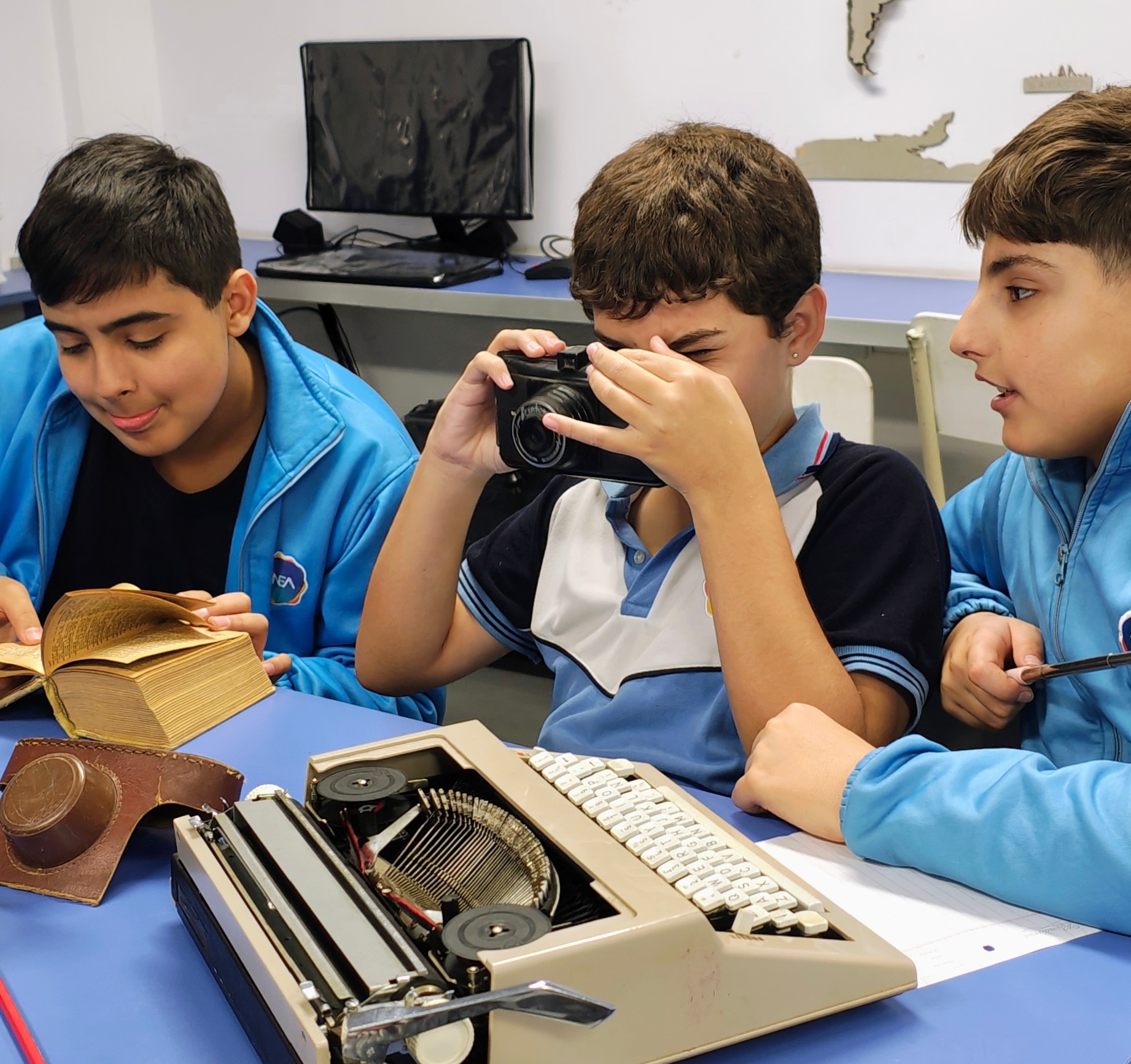 Estudiantes fotografían una máquina de escribir y un libro antiguo